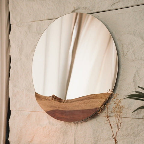A circular live edge wood mirror with a natural wooden frame, showcasing the beauty of raw materials.
