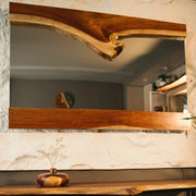 A rectangular mirror framed by two pieces of live edge wood, highlighting the natural beauty and rustic charm of the design.